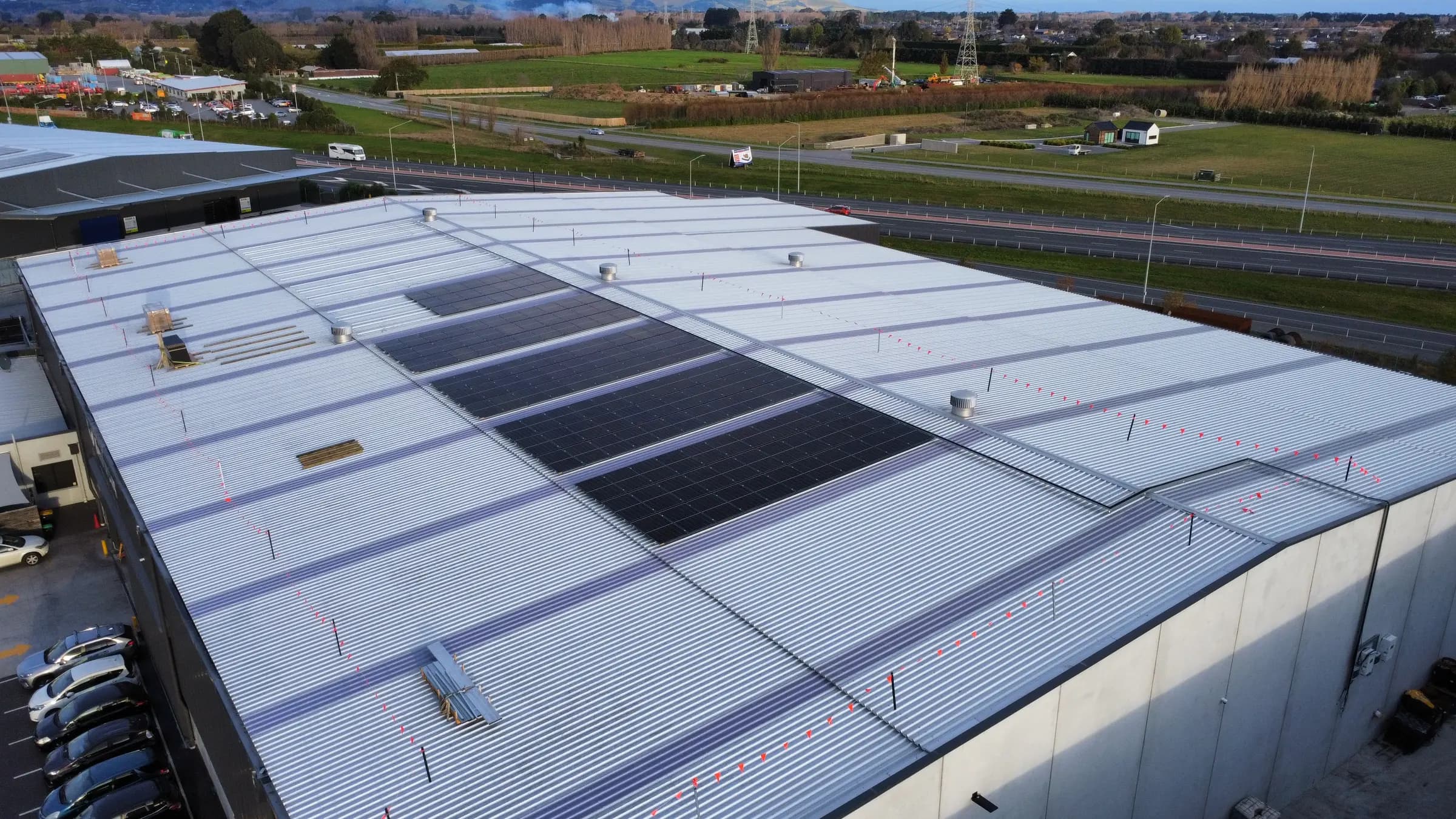 Aerial view of solar panel groups installed across a large industrial roof in Hornby South
